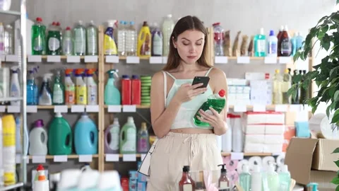 Woman scans QR code on label of detergent using her smartphone, while in the Stock Footage 332637859