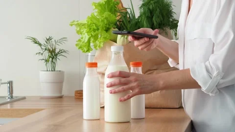 A woman scans a qr code on a milk bottle with her phone. Read the description of Video stock 205450895