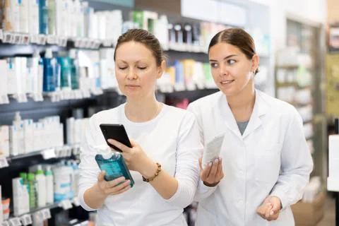 Woman scans QR code on packaging of face cream and listens attentively to Foto stock