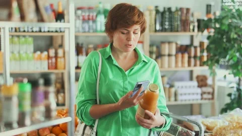 Woman scans a qr code on peach juice. European woman uses mobile phone and pays Stock Footage 317133463