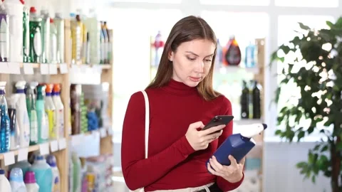 Woman scans qr code of window and glass cleaner. Buyer pays for household Stock Footage 308750477