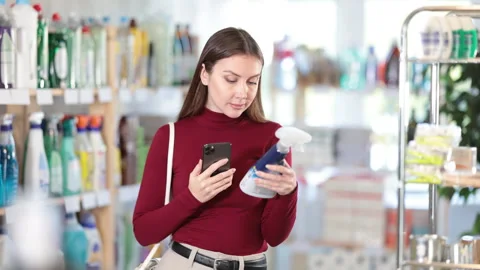 Woman scans qr code of window and glass cleaner. Buyer pays for household Stock Footage 314239904