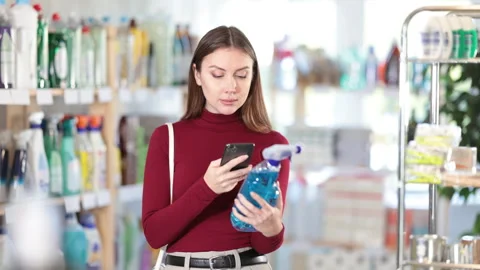 Woman scans qr code of window and glass cleaner. Buyer pays for household Stock Footage 341429364