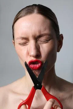 Woman with scissors looking at the camera posing on white background. Vertical. Fotos de archivo