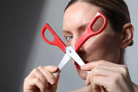 Woman with scissors looking at the camera posing on white background. Close-up. Fotos Stock