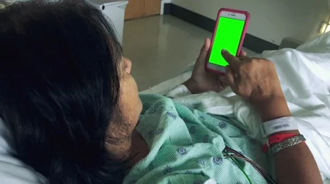 Woman scrolling through smartphone while laying down in hospital bed Stock Footage 56186281