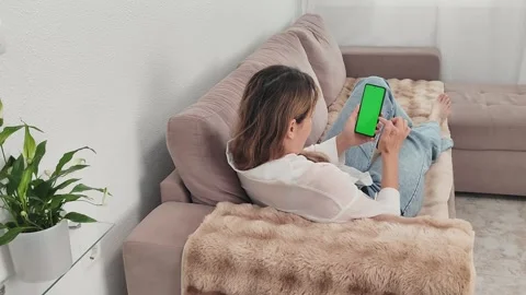 A woman scrolls through the screen of a mobile phone with a green chroma key Stock Footage 276921135