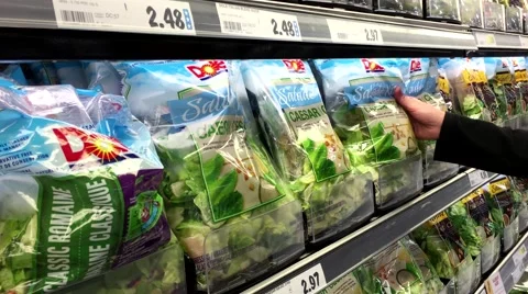 Woman selecting Dole caesar salad kit in grocery store produce department 動画素材 59747584
