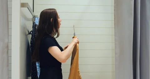 Woman selecting garment from rack in fitting room, rack browsing repeated to Stock-Footage 312580088