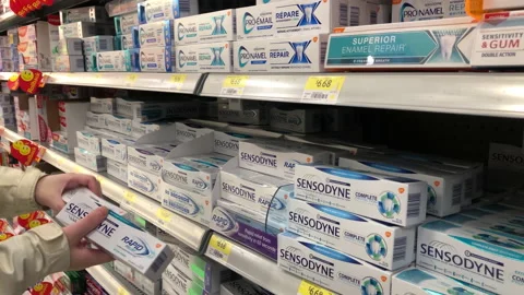 Woman selecting Sensodyne for sensitivity toothpaste inside the Walmart store 스톡 동영상 151643450