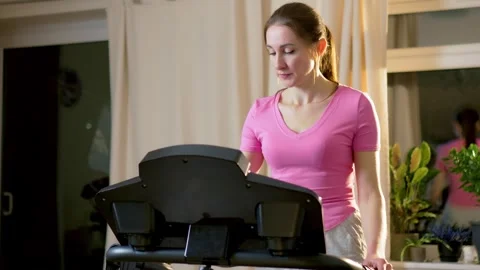 Woman selecting workout program on treadmill console during home cardio training Stock Footage 331207572