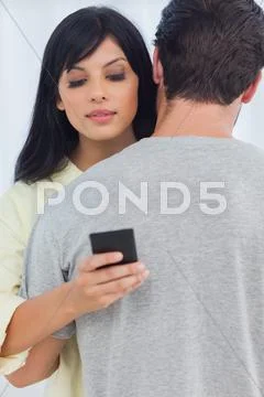 Woman sending text message as boyfriend hugs her Stock Photos