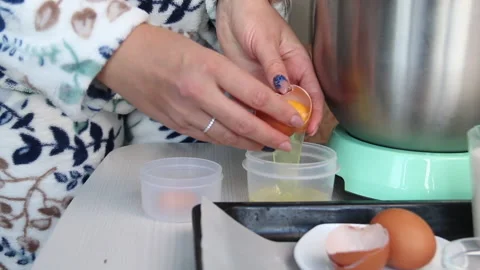 The woman separates the egg white. On the table are the ingredients for makin Stock Footage 210792001