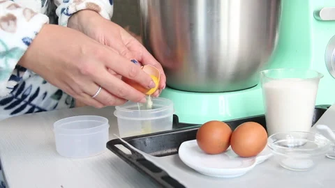 The woman separates the egg white. On the table are the ingredients for makin Stock Footage 210798162