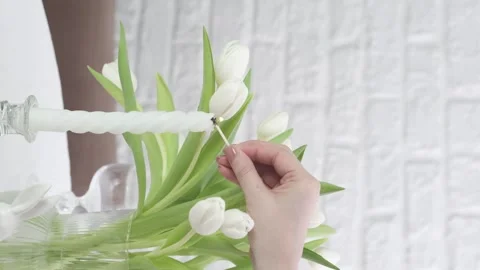Woman served easter table with white flowers, she is burning candles on table in Stock Footage 269749269
