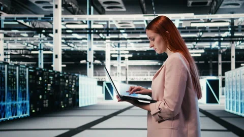 Woman in server farm using laptop to improve electronics optimizations Video stock 330139891