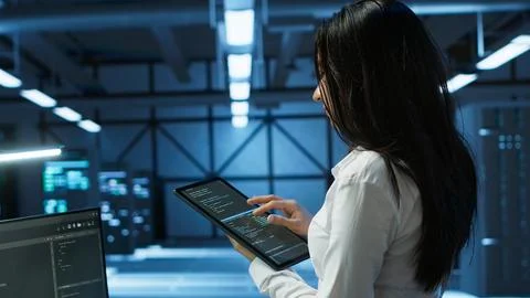 Woman in server room coding on tablet Stock-Fotos