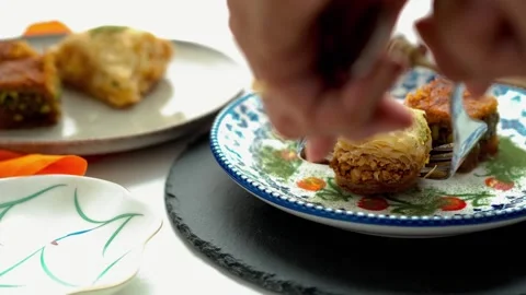 A woman serving baklava from the table onto a small plate with a fork Stock Footage 317916185
