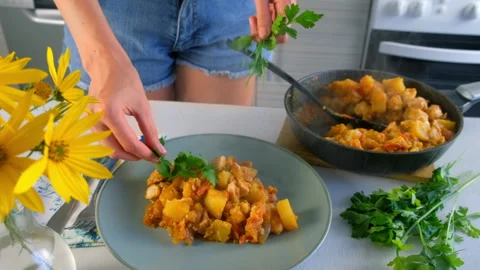 Woman serving cooked vegetables potatoes and chicken meat stew with parsley. Video stock 312469996