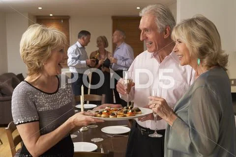 Woman Serving Hors D'oeuvres To Her Guests At A Dinner Party Stock-Fotos