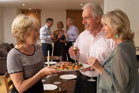 Woman Serving Hors D'oeuvres To Her Guests At A Dinner Party Stock Photos