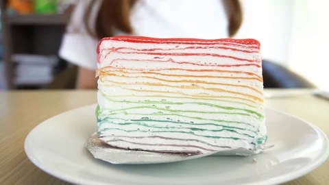 Woman  serving a rainbow crape cake on the table. Video stock 101275240