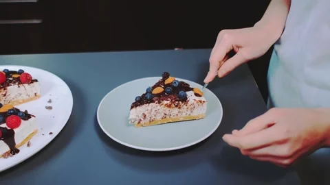 Woman serving a slice of berry cake indoors on a dark surface Видео 342845187