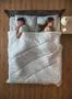 The woman set alarm on the bed near the husband. view from above Photo