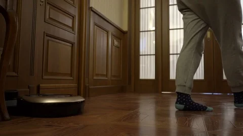 Woman sets the program to the robot vacuum cleaner and it starts moving Stock Footage 102223473