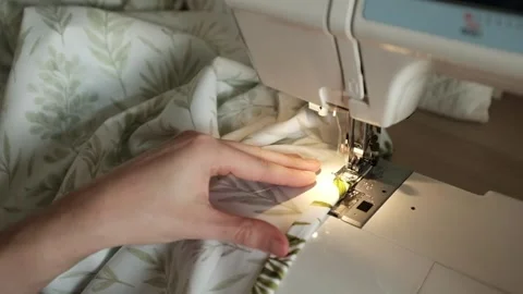 Woman sews bed lined or clothes on sewing machine. Manufacture of textile goods. Stock Footage 316920533