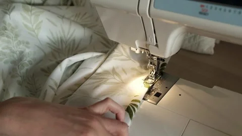 Woman sews bed lined or clothes on sewing machine. Manufacture of textile goods. Stock Footage 316920536