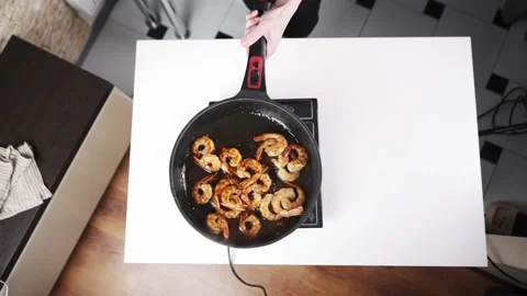 Woman shaking frying pan while cooking shrimps. Slow motion view of a person Stock Footage 231124953