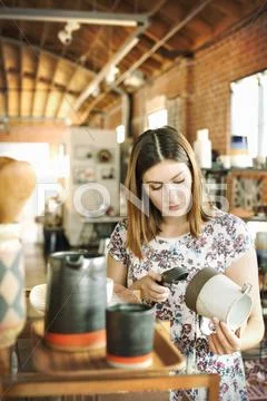 Woman In A Shop, Scanning The Barcode Of A Ceramic Jug