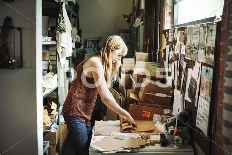 Woman in a shop wrapping merchandise in brown paper. Stock Photos