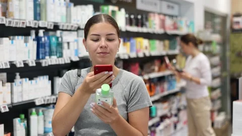 Woman shopper using smartphone scans qr code on label in pharmacy Stock Footage 332637356
