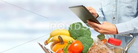 Woman with shopping cart and tablet computer. Stock Photos