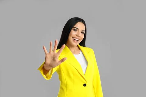Woman showing number five with her hand on grey background Stock Photos