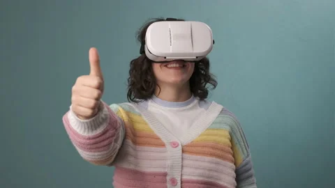 Woman showing thumb up while using VR virtual reality headset over an blue ba Stock Footage 205048724