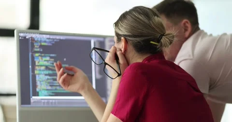 Woman shows program coding on computer monitor to colleague Stock Footage 285664904
