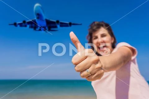 Woman shows a ring with an airplane have fun on the beach watching the landing Stock Photos