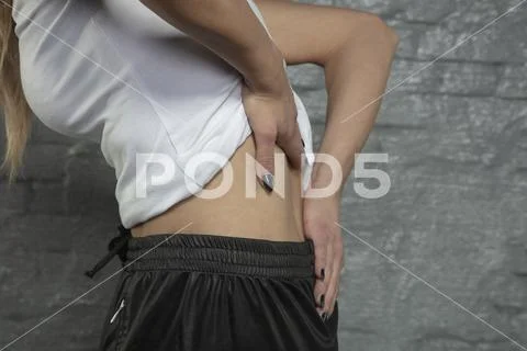 Woman shows that she has back pain, bending forward Stock Photos
