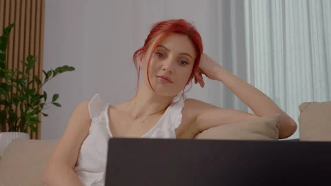 Woman shows surprise while watching something interesting on her laptop Stock Footage 329231353