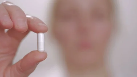 Woman shows a tablet while holding it with her fingers, then swallows it and Stock Footage 101076898