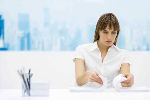 Woman shuffling two stacks of paper together, sitting at desk Stock Photos