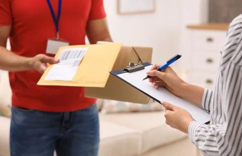 Woman signing for delivered parcels at home, closeup. Courier service Stock Photos