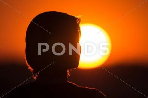 The woman (silhouette) stand by bright sun and sky background. Close up Stock Photos