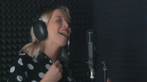Woman singer in headphones singing in microphone recording song in sound studio. Stock Footage