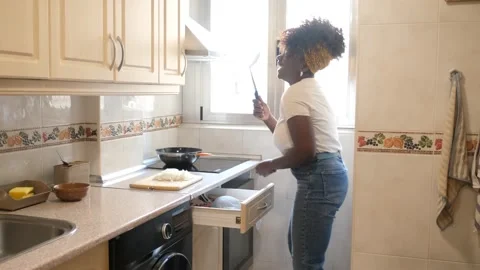 Woman singing and dancing while cooking in kitchen Stock Footage 284114672