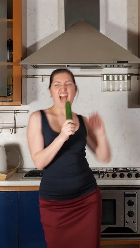 Woman singing and dancing while holding a cucumber as a microphone, feeling Stock-Footage 344823356