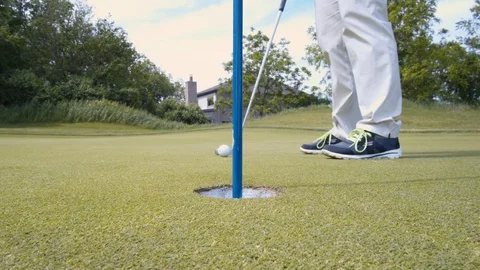 Woman sinks a putt on the golf course Stock Footage 129761982